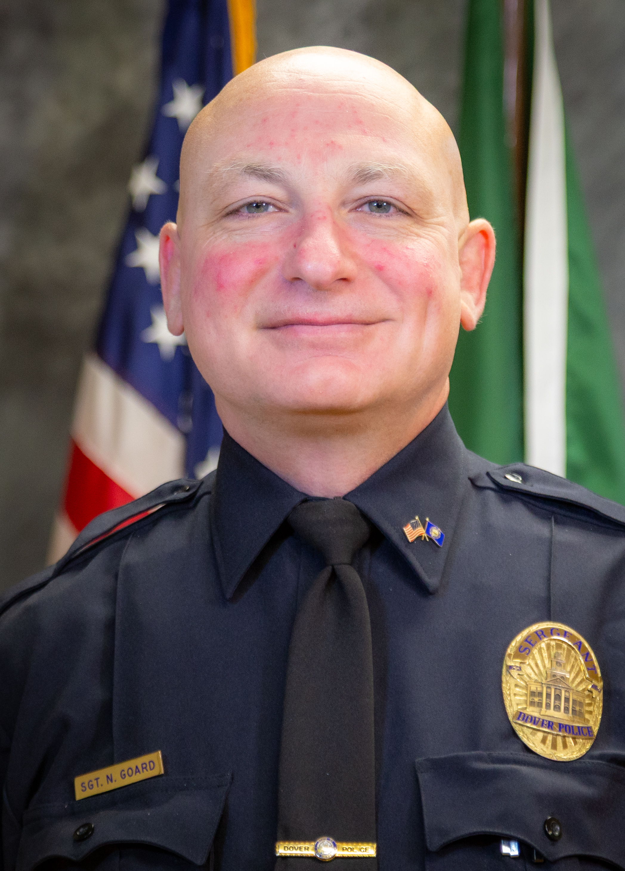 Man in front of flags of US and Dover NH
