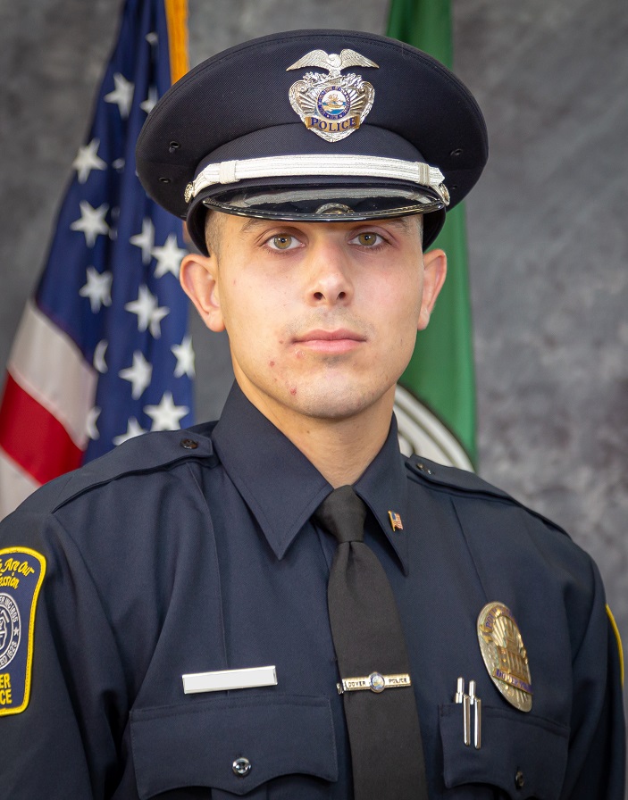 Police Office Adin Sobel in a police cap and uniform in front of the US flag 