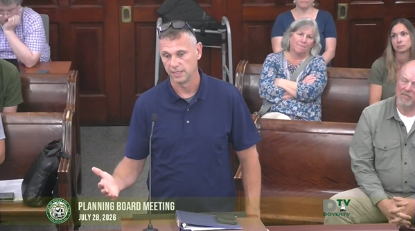 Video screenshot of Planning Board meeting on July 28 2026. A applicant stands at the podium